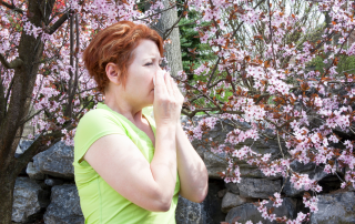 woman blowing her nose in front of blooming flowers because of Las Vegas allergies
